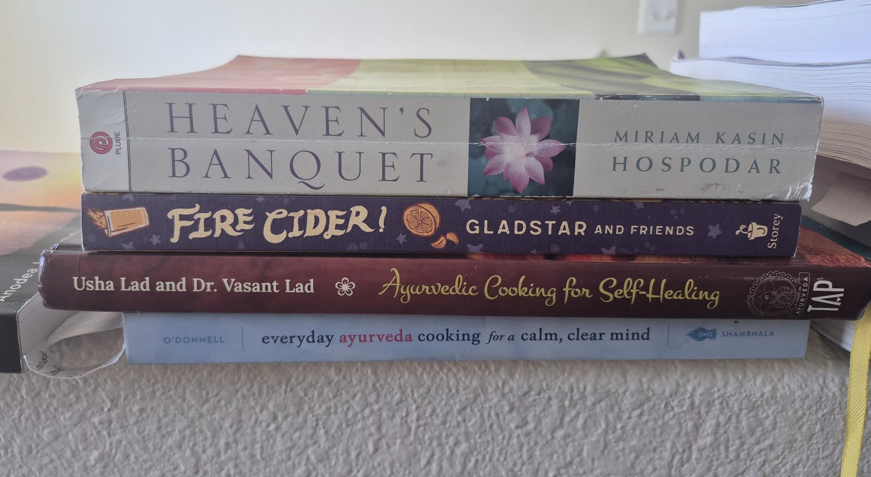 A stack of PJ’s cookbooks: Heaven’s Banquet, Fire Cider!, Ayurvedic Cooking for Self-Healing, and Everyday Ayurveda Cooking for a Calm, Clear Mind.